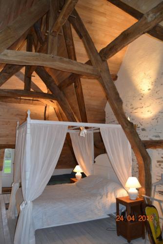 - une chambre avec un lit à baldaquin et des plafonds en bois dans l'établissement Manoir de Belle-Noë, à Dol-de-Bretagne