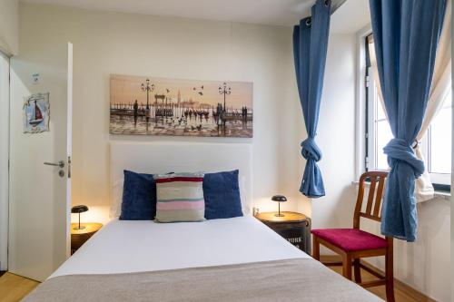 a bedroom with a bed with blue curtains and a window at Family House in Aveiro