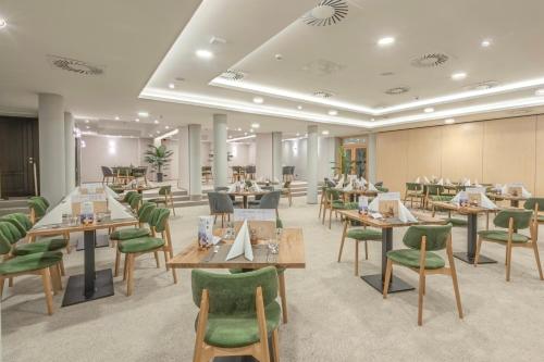 a restaurant with wooden tables and green chairs at AquaMed Hotel Harkány in Harkány