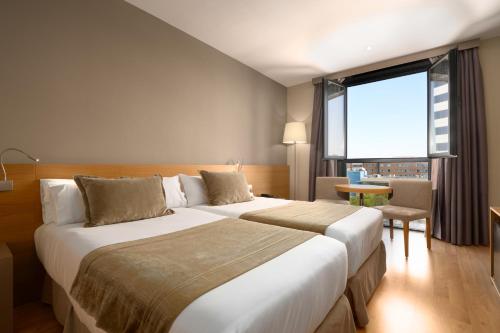 a hotel room with two beds and a large window at M.A. Hotel Sevilla Congresos in Seville