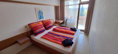 a bedroom with a bed with colorful pillows and a window at Ferienresort mit Pool am Schluchsee in Schluchsee