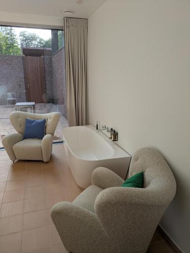 a bathroom with two chairs and a bath tub at Herman in Bruges