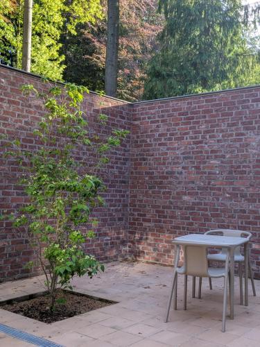 a table and a bench next to a brick wall at Herman in Bruges