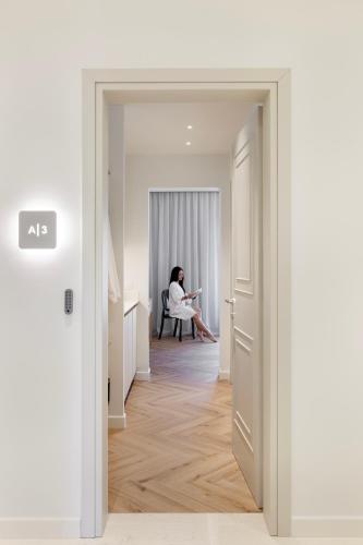 a woman sitting in a chair in a white room at Heronia Suites in Karistos