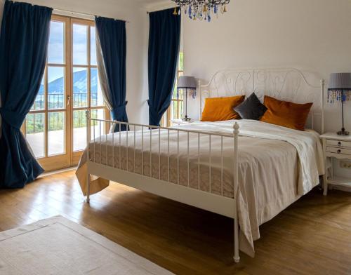 a bedroom with a large white bed with blue curtains at Santa Barbara House in Ratiševina
