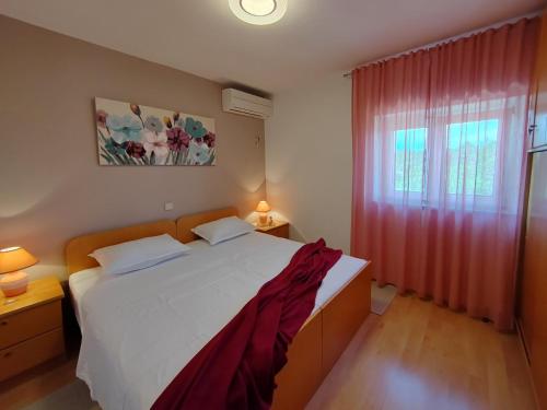 a bedroom with a white bed and a red curtain at Apartments Damir in Sveti Ivan Dobrinjski