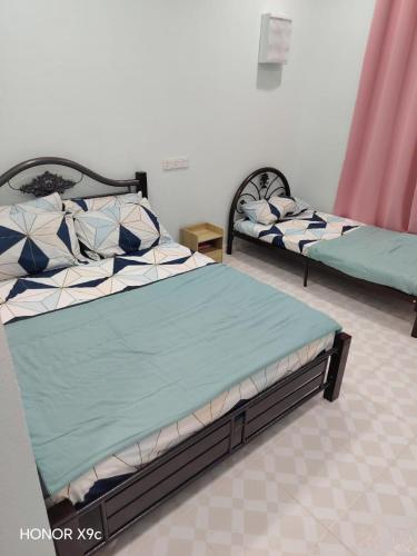 two beds sitting next to each other in a room at ZIRA STAY PENARIK - Nuha Room in Kampong Ru Sepuloh
