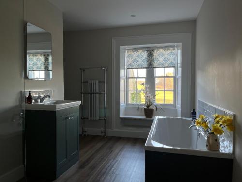 a bathroom with a tub and a sink and a window at Halton Red House Farm in Stagshaw Bank
