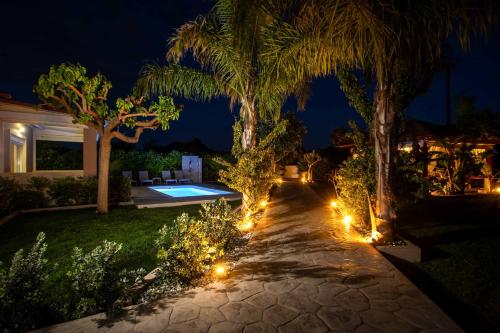 a garden with lights and palm trees at night at Sea Breeze & Nature villa, with heated pool and garden retreat in Kremasti