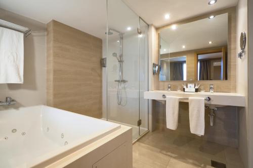 a bathroom with a tub and a sink and a shower at M.A. Hotel Sevilla Congresos in Seville