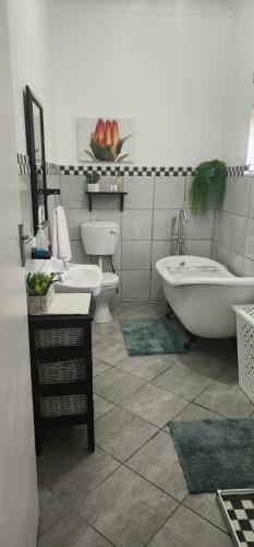 a bathroom with two toilets and a tub and a sink at The Garden Inn Guesthouse in Modimolle