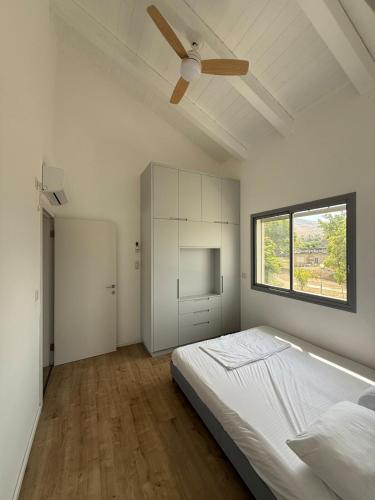 a white bedroom with a bed and a window at שחף על הכנרת in HaOn