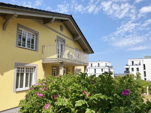 a yellow house with a balcony and flowers at Haus Strandkiefer in Baabe