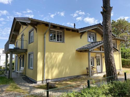 a yellow house with a tree in front of it at Haus Strandkiefer in Baabe