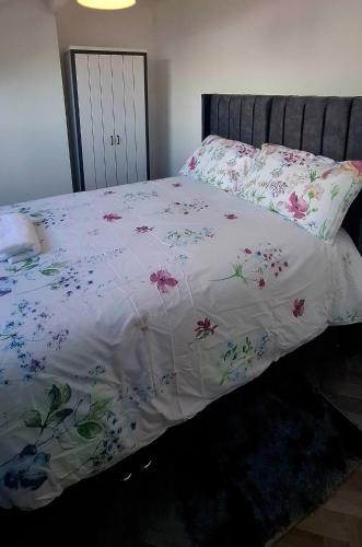 a bed with a white comforter with flowers on it at Stratford Terrace in Beeston