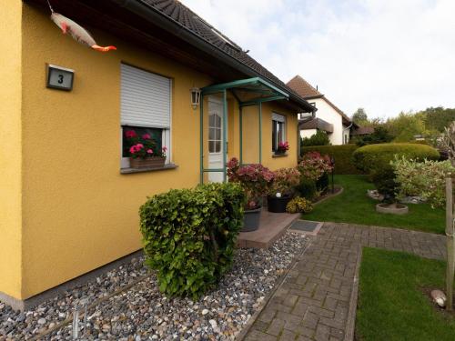 a yellow house with flowers in a yard at Ferienwohnung Kranich - Dranske in Dranske