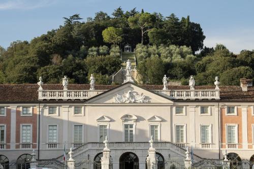 a large white house with a hill in the background at Villa Fenaroli Palace Hotel in Rezzato