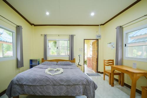 a bedroom with a bed and a table and windows at Baanrimklong bungalow in Ko Chang