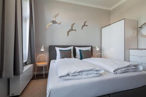 a bedroom with a white bed with birds on the wall at App Flamingo in Kühlungsborn