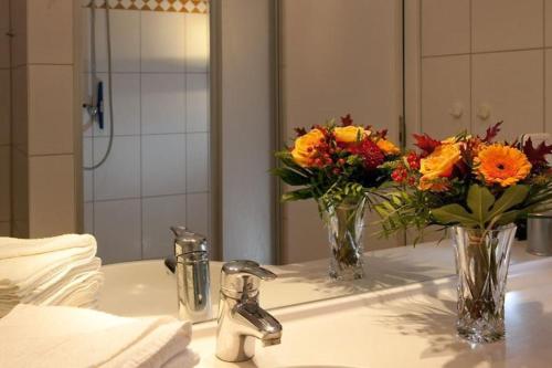 a bathroom sink with a vase of flowers on it at Störtebeker 07 in Kühlungsborn