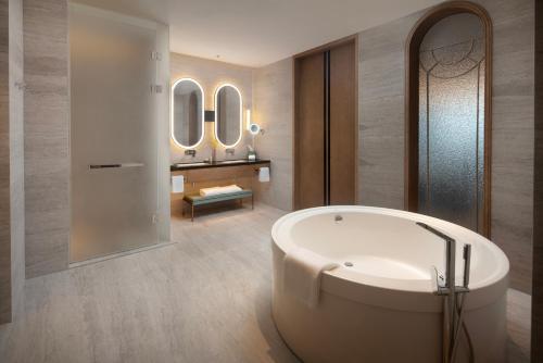 a bathroom with a white tub and a sink at Bristoria Hotel Yangzhou in Yangzhou