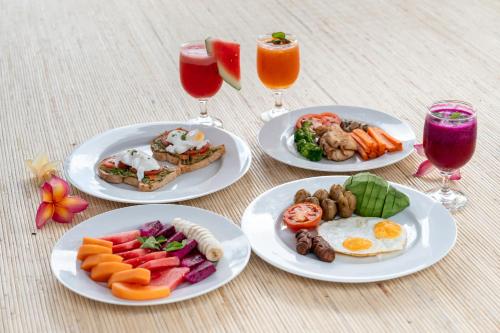 a table with plates of food and two glasses of juice at Ulu Apsura Villas in Uluwatu