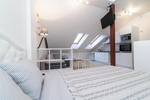 a white bedroom with a bed and a kitchen at Vilnius Old Town Happiness in Vilnius