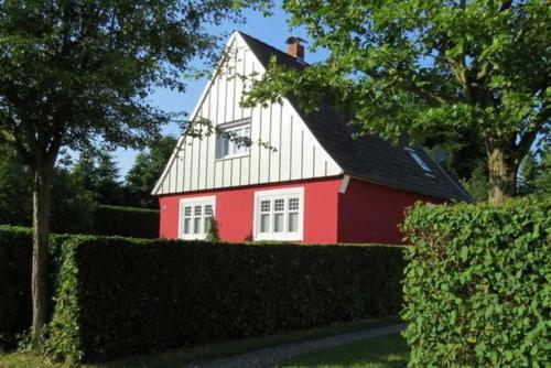 a red and white house behind a hedge at "Ferienhaus Großenaspe" in Großenaspe