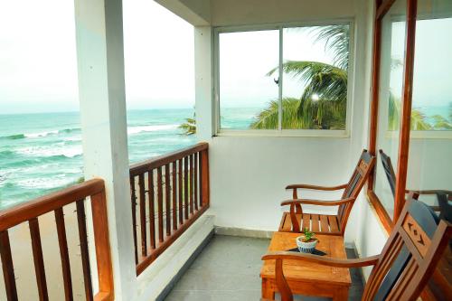 a porch with two rocking chairs and the ocean at Cozy Cocos Midigama in Ahangama