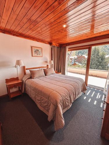 a bedroom with a bed and a large window at Hotel Catedral Patagonia Ski & Wellness in San Carlos de Bariloche