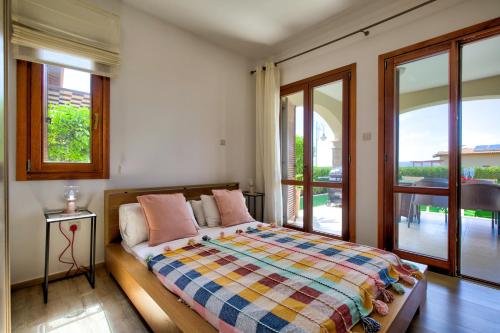 a bedroom with a bed with a view of a balcony at Ground floor Apartment Anthos with Beautiful Sea Views on Aphrodite Hills Resort in Kouklia