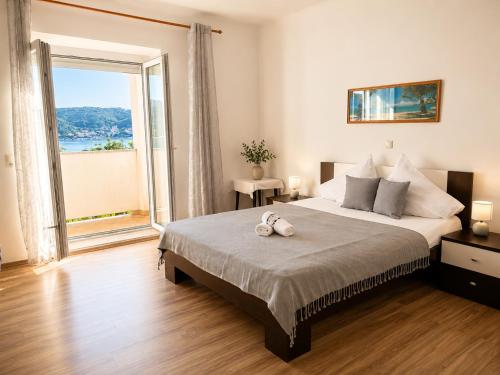 a bedroom with a large bed and a large window at Pljesa Apartments -Meerblick mit Terrasse & Grill by rentyourhome24 in Supetarska Draga