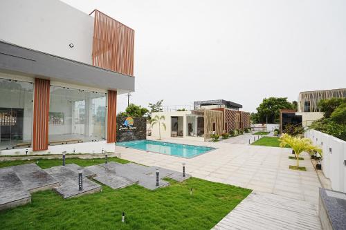 an external view of a building with a swimming pool at Sandy Resort in Agastīswaram