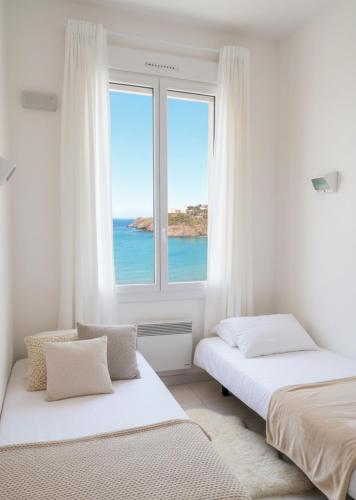 two beds in a room with a window at Résidence les 4 Horizons in Cerbère
