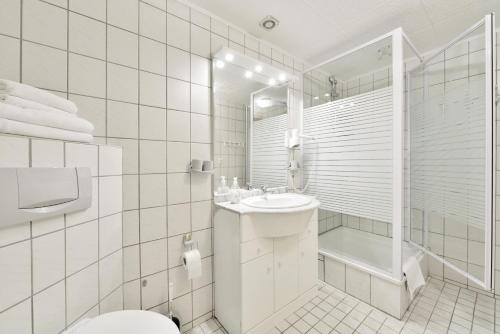 a white bathroom with a toilet and a sink at Hotel Gesellschaftshaus in Bergen auf Rügen