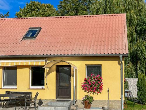 a yellow house with a red roof with a table and flowers at Luzie's Hus in Freest