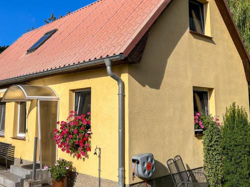 a yellow house with a red roof and flowers at Luzie's Hus in Freest