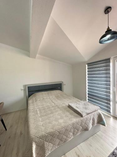 a white bedroom with a bed and a window at RADUGA West in Koshkolʼ