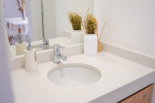 a bathroom sink with two vases with flowers on it at Temporario Sur, Depto ideal familias con cuna Pet-friendly, zona IUPA in General Roca
