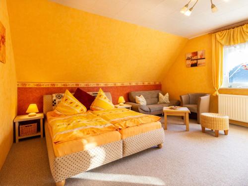 a yellow bedroom with a bed and a couch at Ferienwohnung Familie Schmidt in Bergen auf Rügen