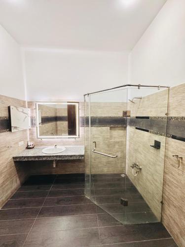 a bathroom with a glass shower and a sink at Holiday One Hotel & Suites - DHA-8 in Karachi