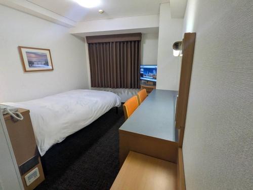 a small hotel room with a bed and a desk at Hotel Alpha-One Yokohama Kannai in Yokohama