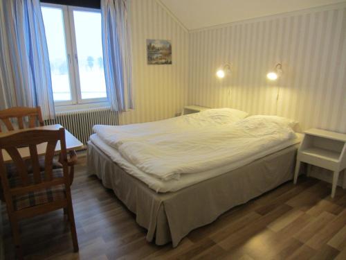 a bedroom with a bed and a chair and a window at Sörnäsgården Bed & Breakfast in Lima