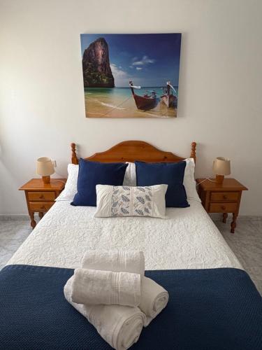 a bedroom with a bed with blue pillows and a painting at El paraíso in Raxó