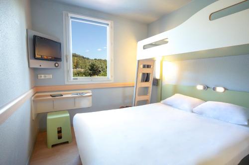 a bedroom with a white bed and a window at ibis budget Brignoles Provence in Brignoles
