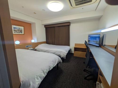 a hotel room with two beds and a flat screen tv at Hotel Alpha-One Yokohama Kannai in Yokohama