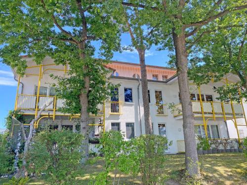 a large white house with a balcony and trees at Villa Störtebeker - Whg 05 in Baabe