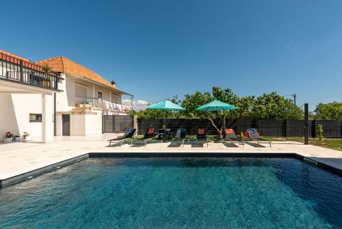 a swimming pool with chairs and umbrellas at Villa Flora Zadar Villas in Perušić Benkovački