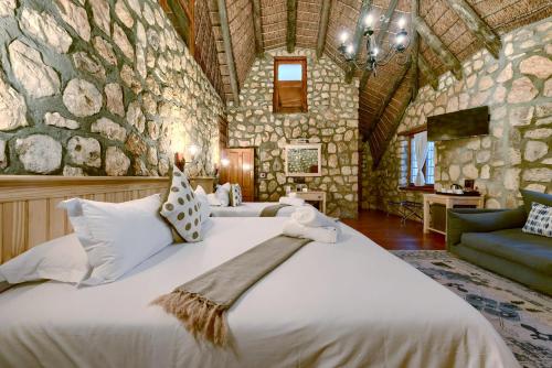 a bedroom with two beds in a room with a stone wall at Arniston Hotel Manor House in Arniston