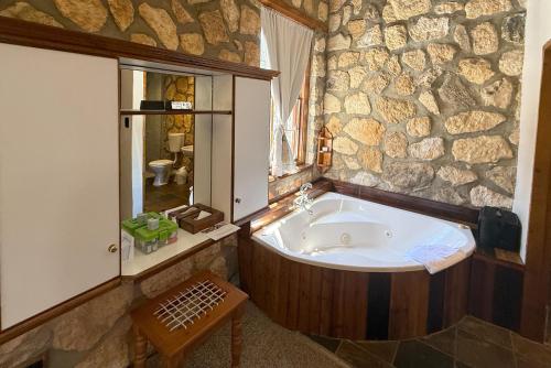 a bath tub in a bathroom with a stone wall at Arniston Hotel Manor House in Arniston